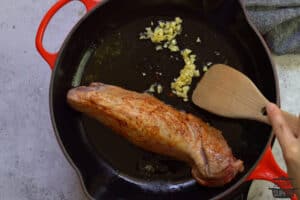 cooking garlic in pan next to pork tenderloin