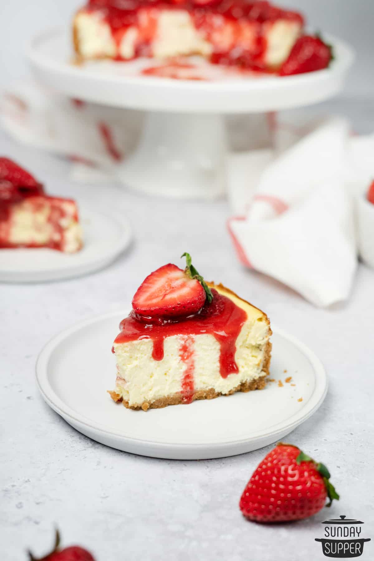 a slice of strawberry cheesecake on a white plate