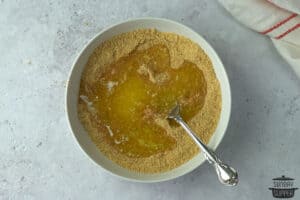 melted butter in a bowl with crushed graham cracker