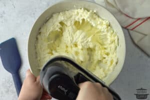 beating cream cheese in a mixture bowl