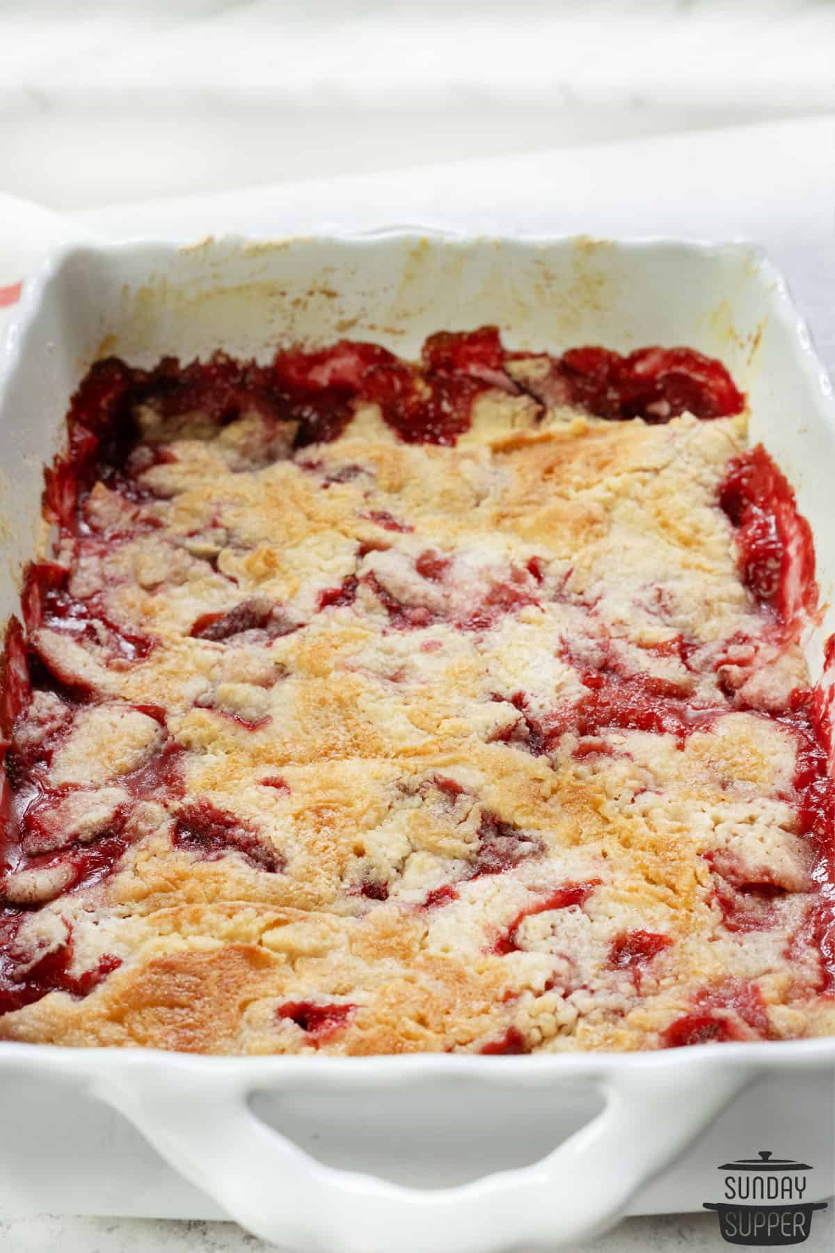 beautiful strawberry dump cake at an angle in a white dish
