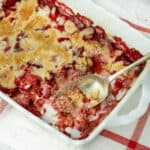 strawberry dump cake with a serving spoon in a baking dish