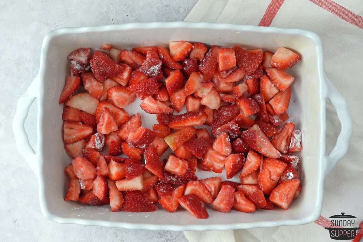 fresh strawberries added to a baking dish