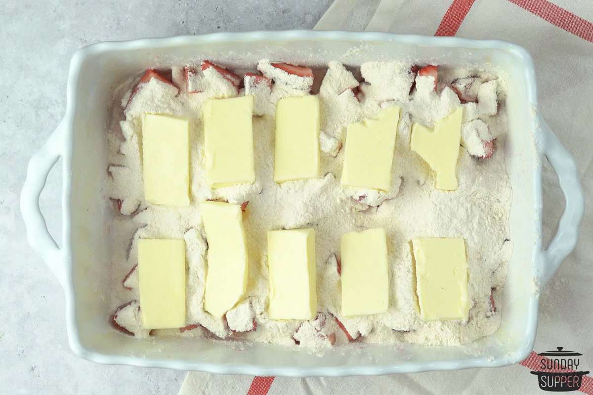 butter slices placed on top of dump cake ready to bake