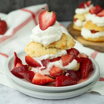 strawberry shortcake with homemade biscuits on a plate with fresh juicy strawberries and whipped cream