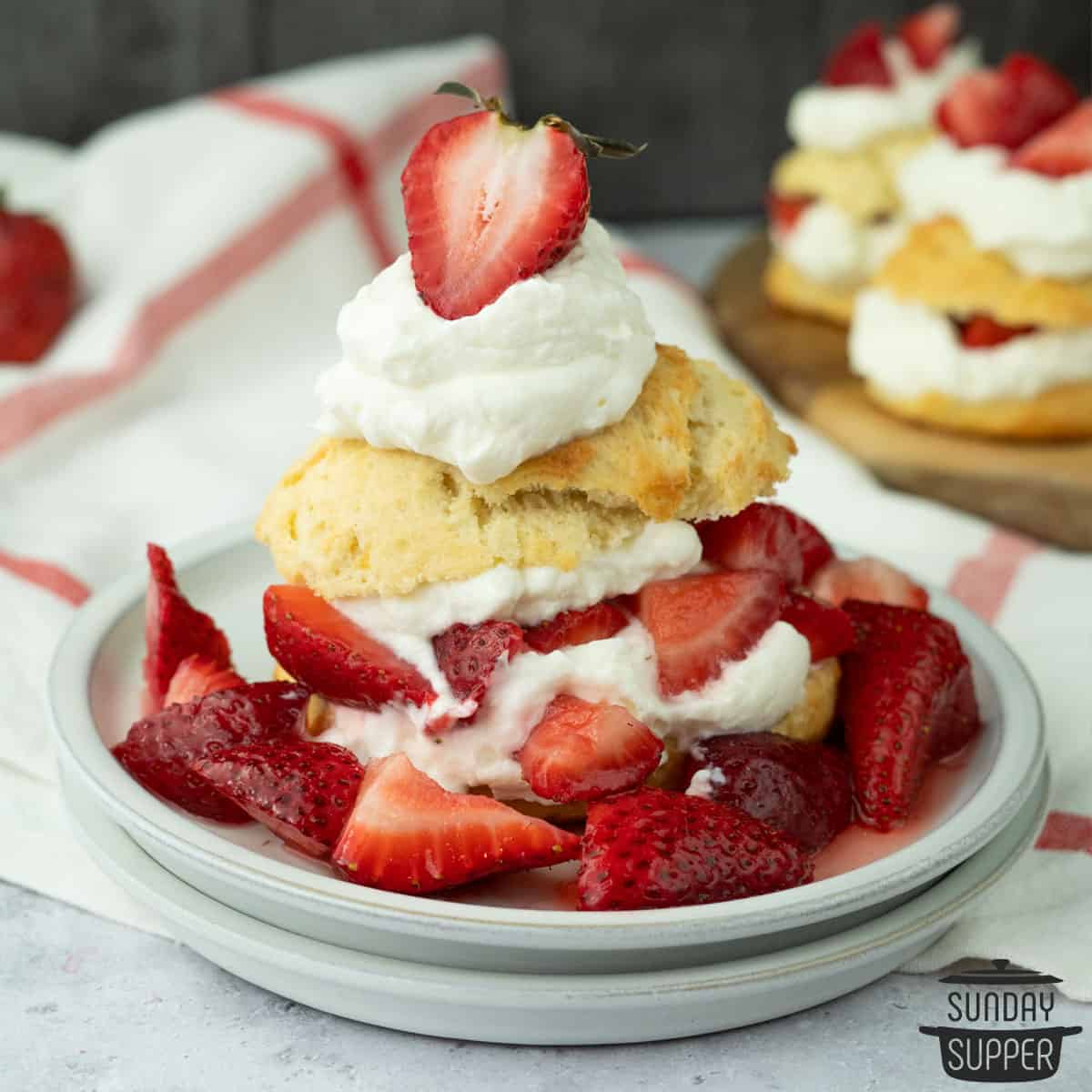 strawberry shortcake with homemade biscuits on a plate with fresh juicy strawberries and whipped cream