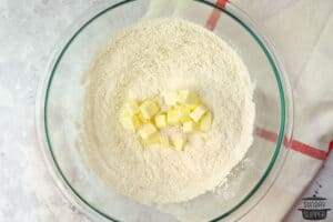 adding cubed butter to flour mixture in bowl