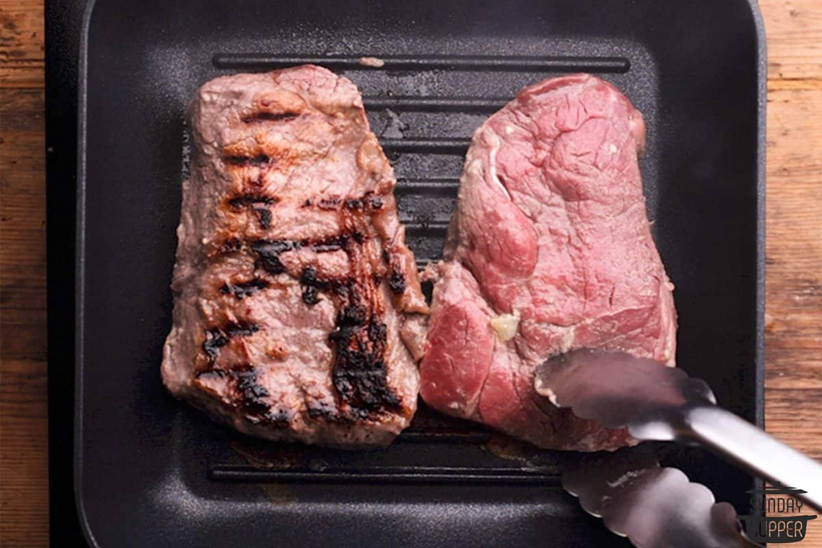 Flipping sirloin steaks in a grill pan using tongs