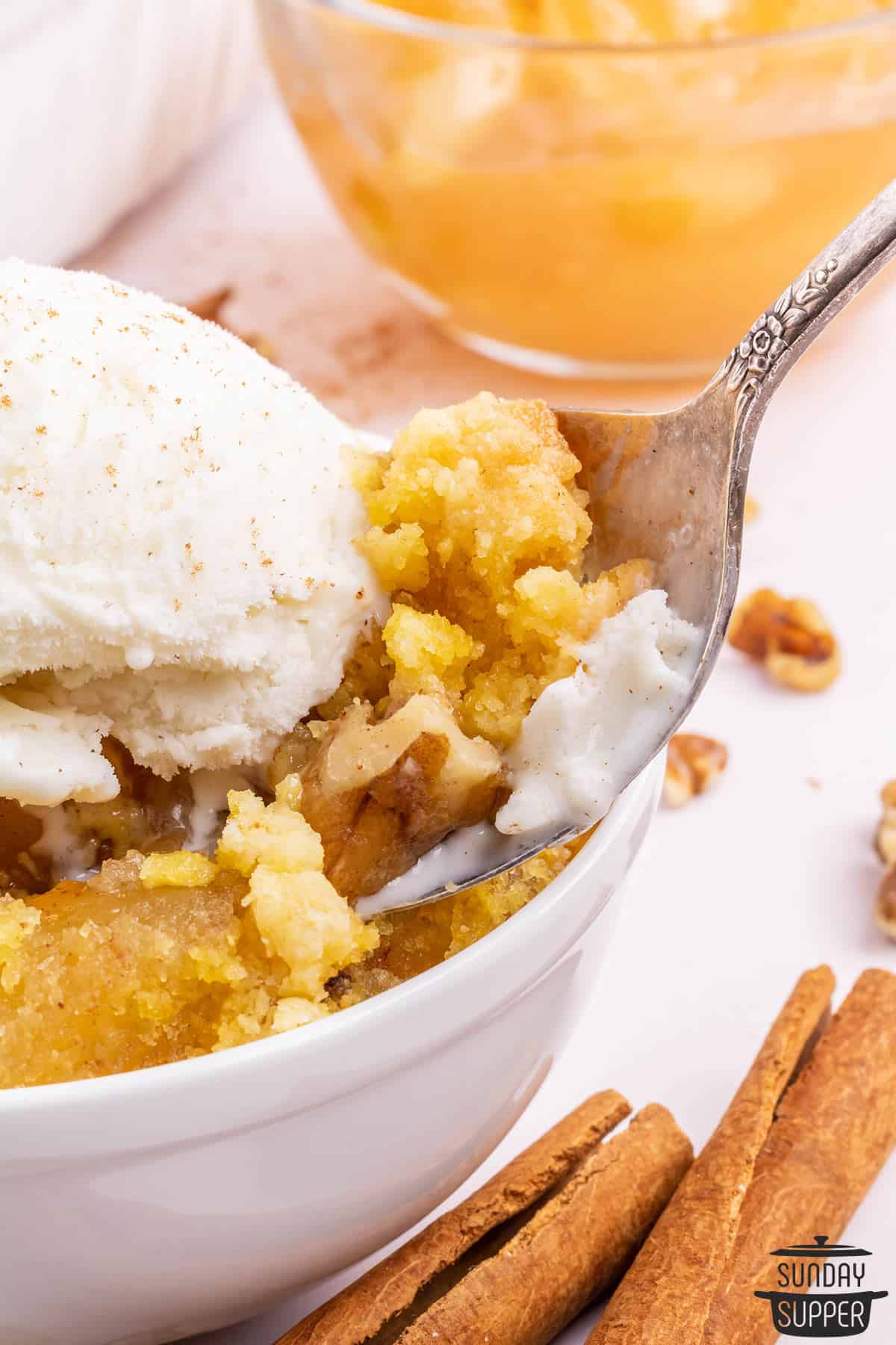 apple dump cake in a white dish with a spoonful