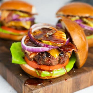 three barbecue burgers on a serving board