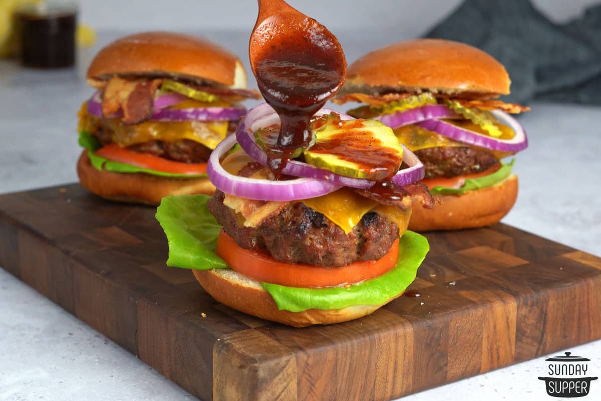 pouring BBQ sauce over a barbecue burger