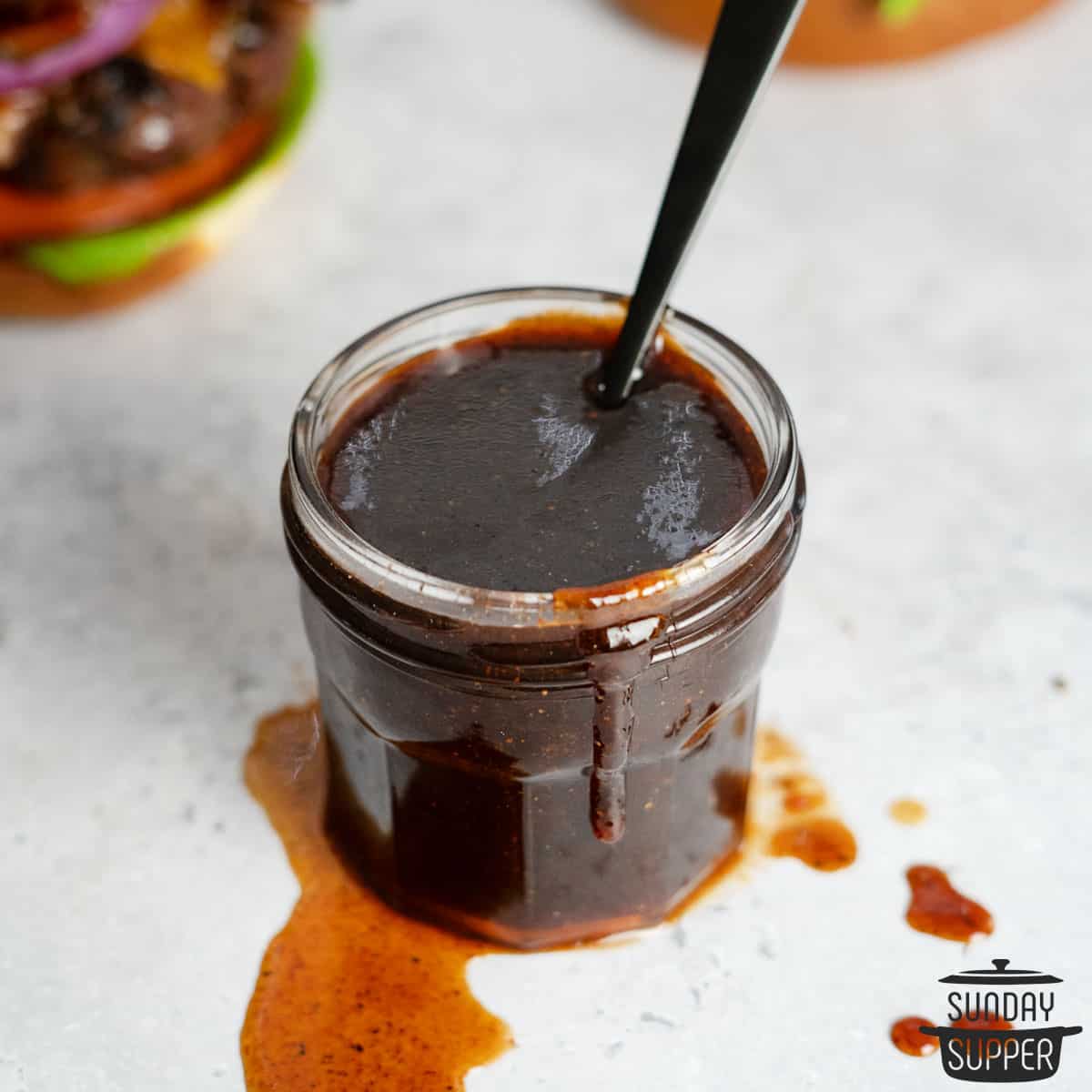 bbq sauce in a clear jar with a spoon inside