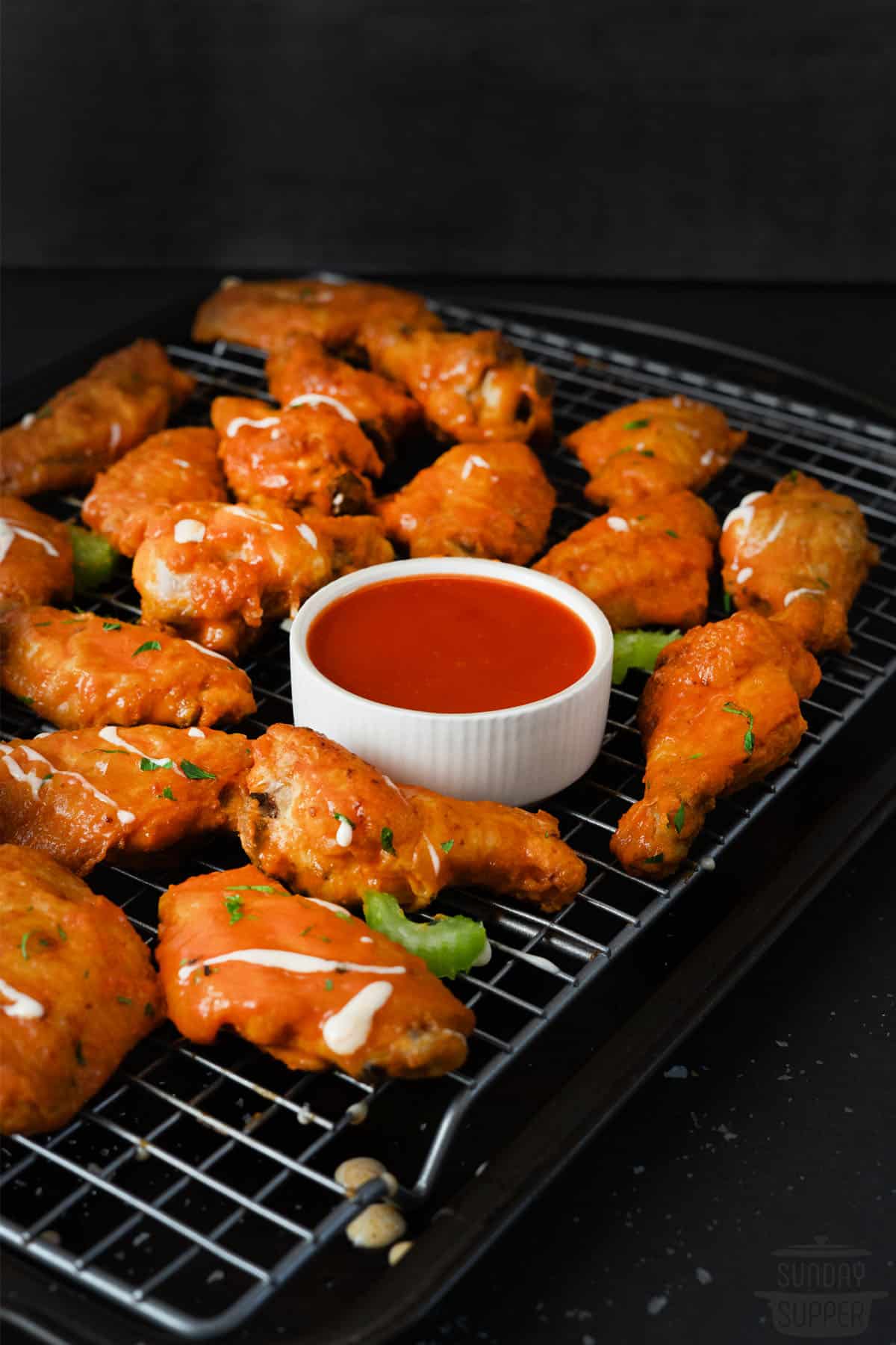 buffalo chicken wings with a cup of buffalo sauce in the middle