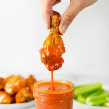 chicken wing dipping into buffalo sauce