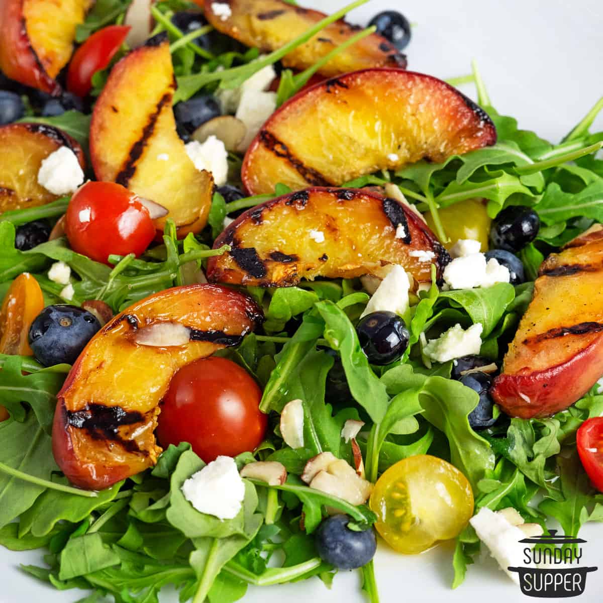 close up of grilled peach salad on a white plate