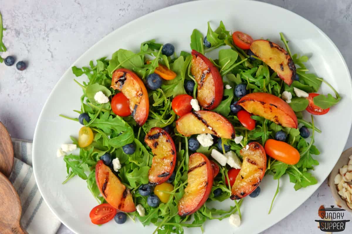 adding feta cheese to grilled peach salad