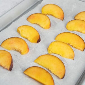 sliced peaches on a baking sheet lined with parchment paper