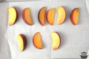 sliced peaches on a baking sheet lined with parchment paper