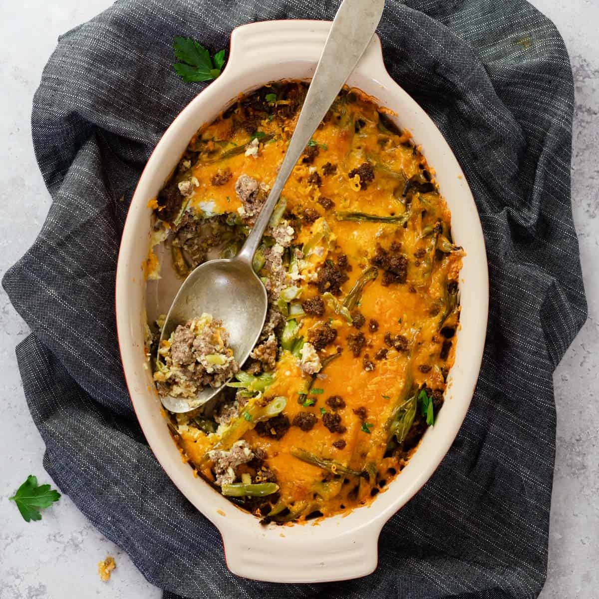 hamburger casserole in a baking dish with a serving spoon