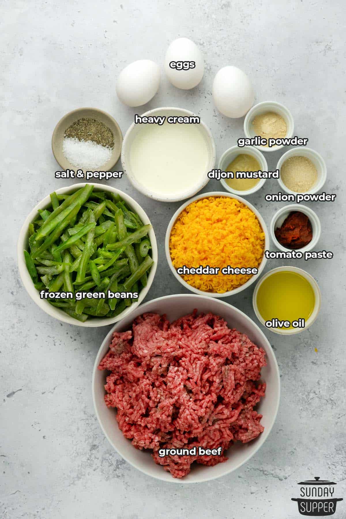 ingredients to make hamburger casserole with labels on a white surface