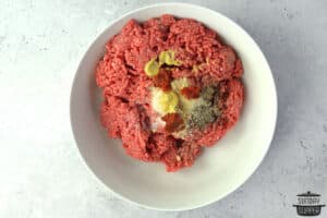 mixing ground beef with seasonings