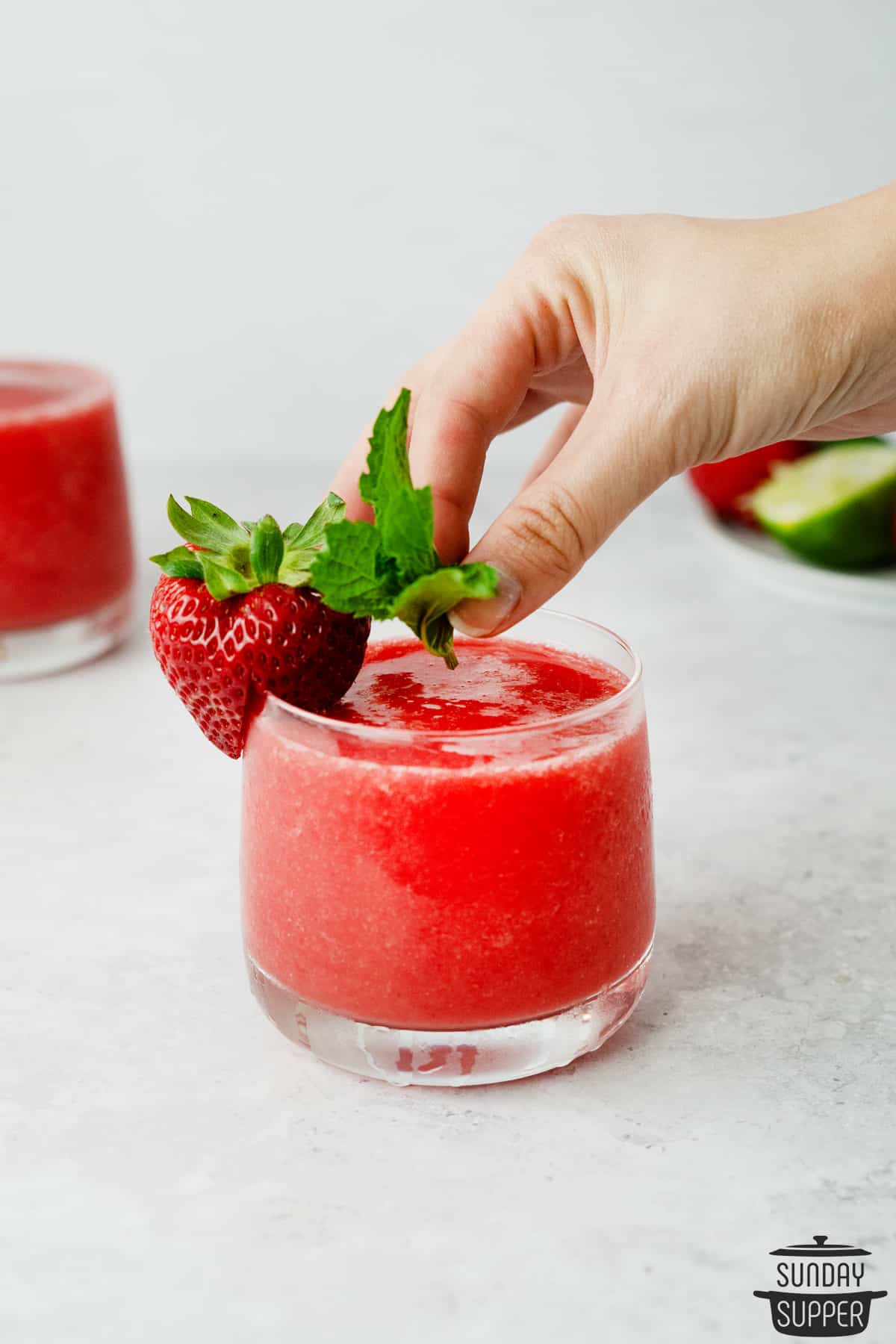 adding mint to the rim of a glass filled with strawberry daiquiri