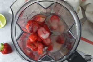 adding strawberry daiquiri ingredients into a blender