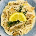 a bowl of ricotta chicken pasta with a lemon wedge and thyme