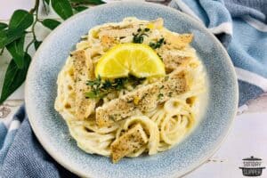 sliced chicken topping a bowl of lemon ricotta pasta with an extra lemon slice and fresh thyme