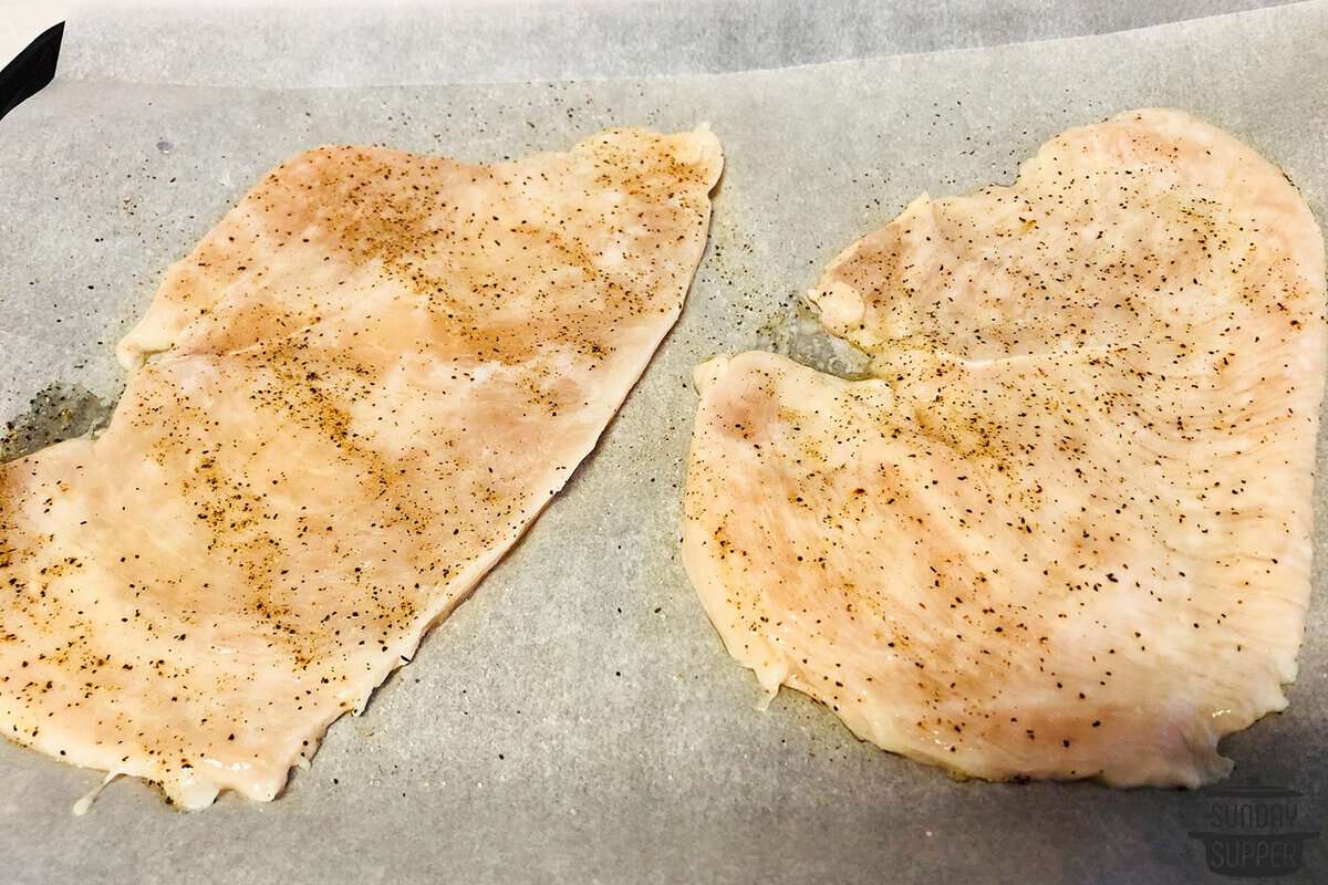 two chicken breasts seasoned with salt and pepper after marinating