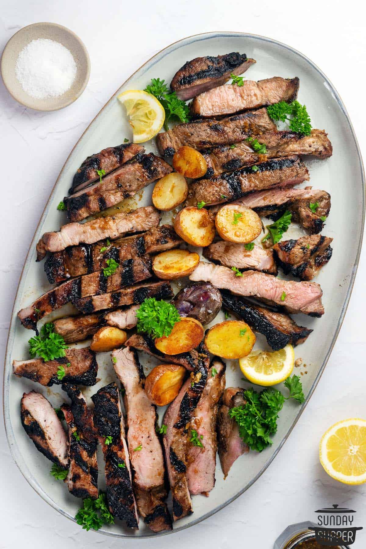 sliced pork steaks with potaotes and lemons on a cutting board