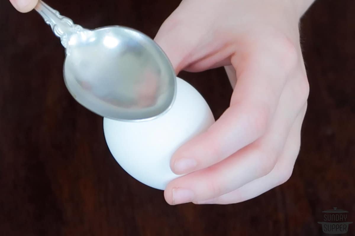 a spoon tapping on the bottom of the egg