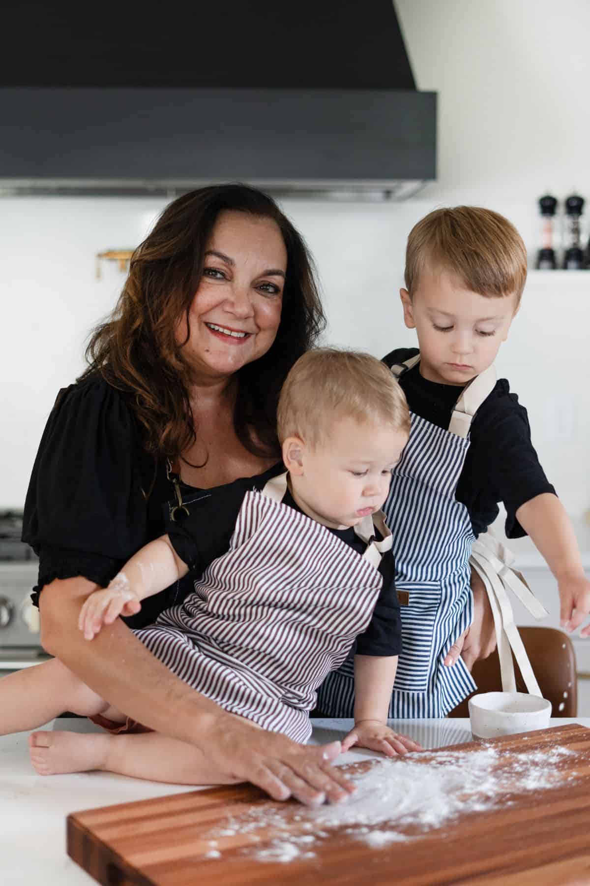 Isabel with her grandchildren and a cutting board with flour