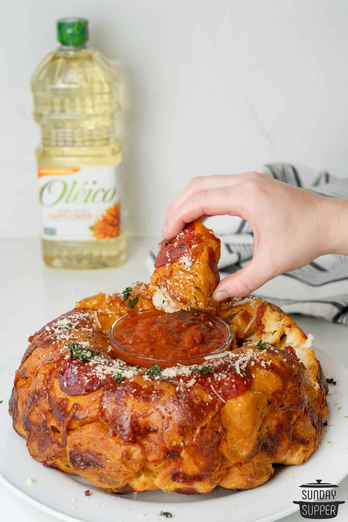 dipping a piece of pizza monkey bread in marinara sauce