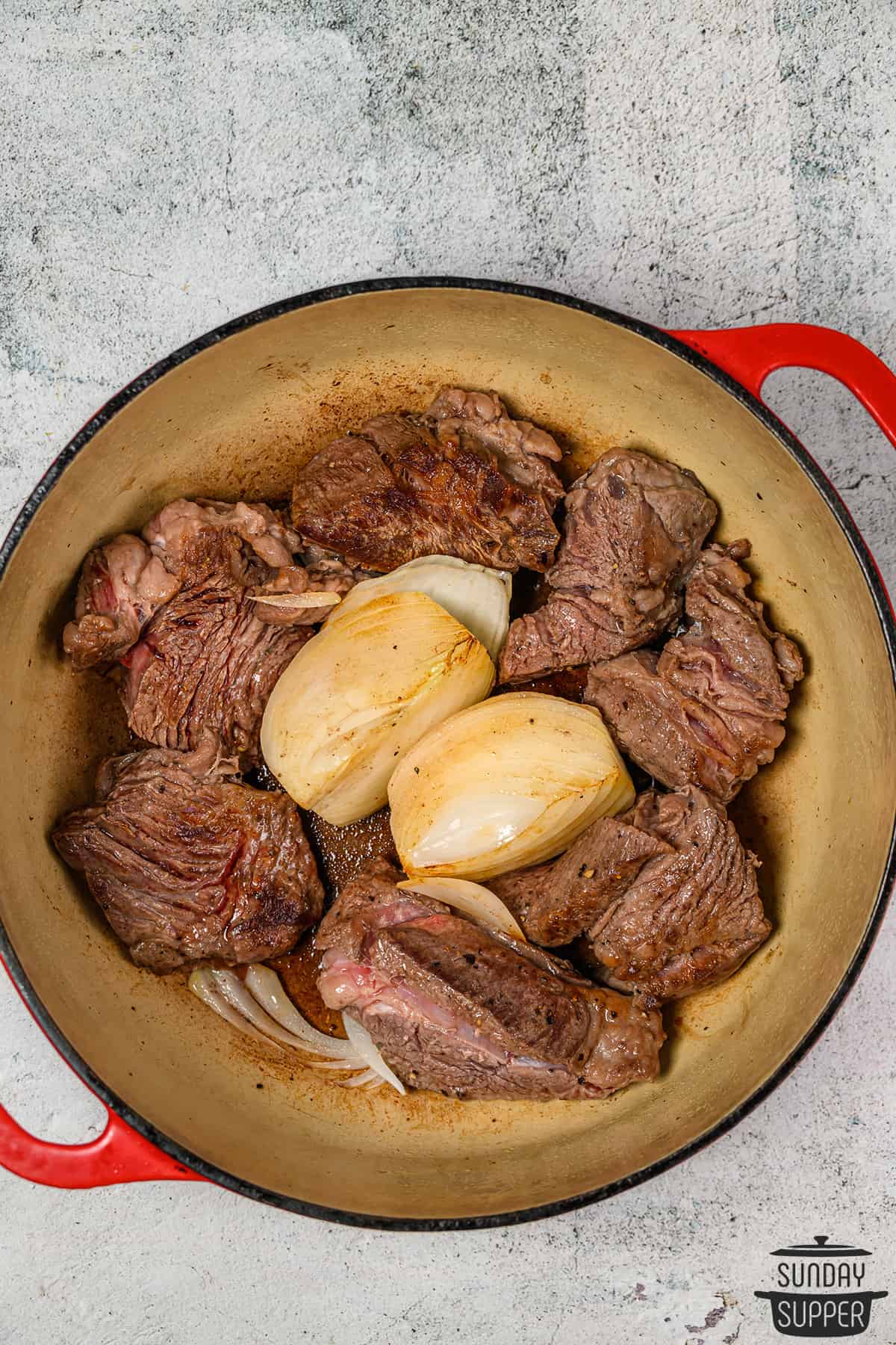 onions and beef birria meat in a pot