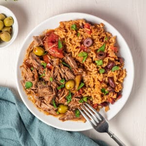 ropa vieja on a plate with beans and rice