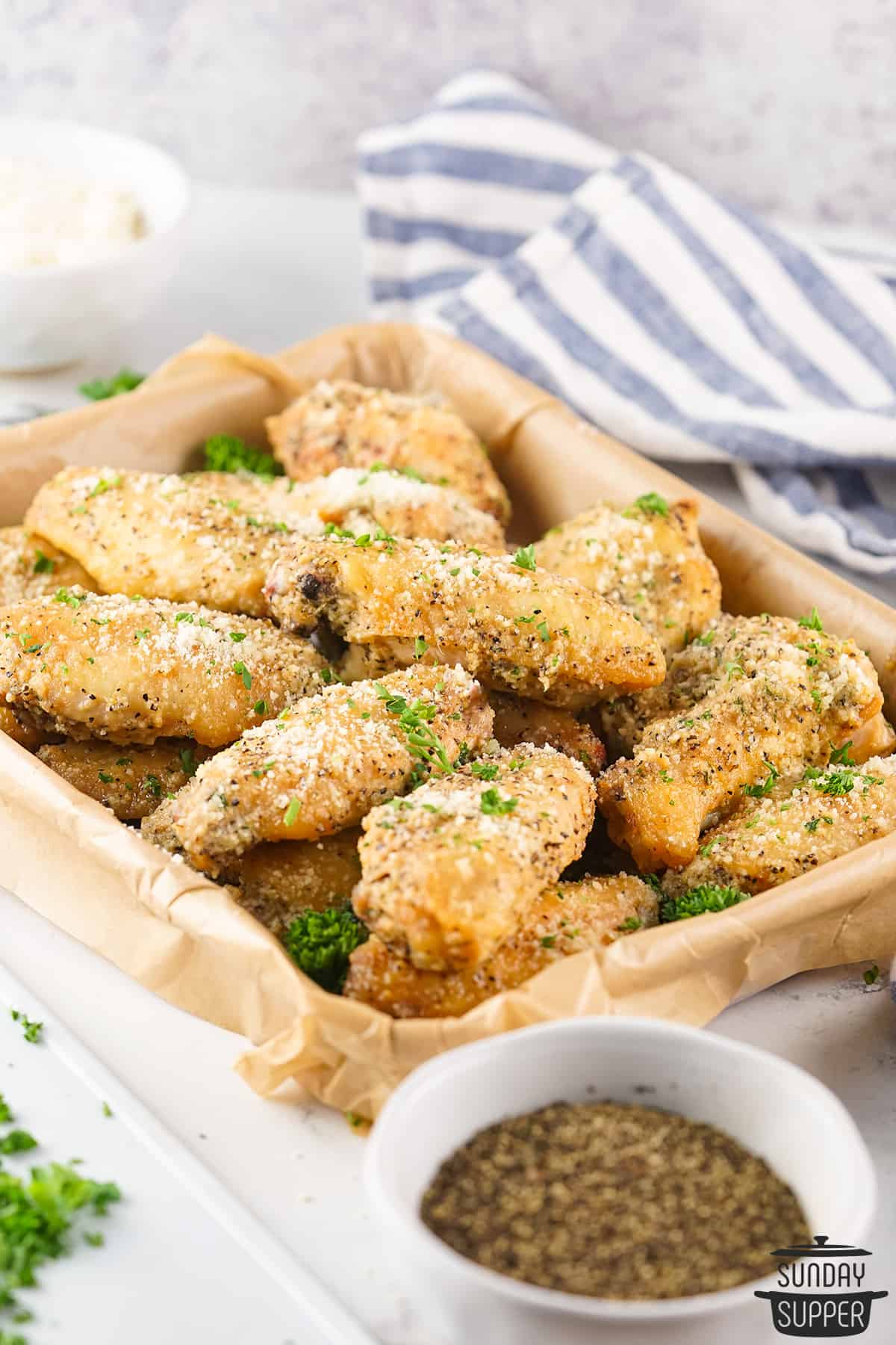 smoked chicken wings with garlic parmesan sauce on a parchment-lined tray