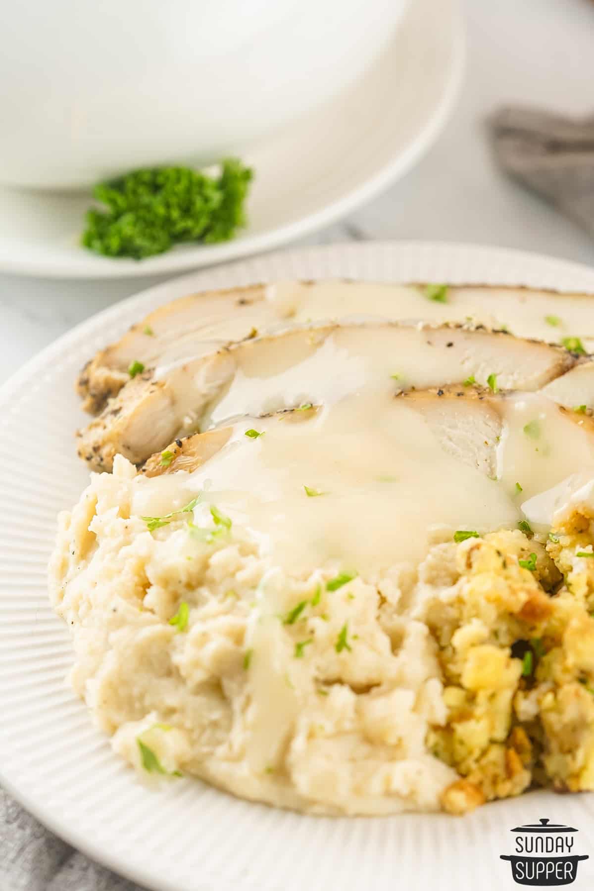 turkey gravy poured over turkey breast, stuffing, and mashed potatoes on a plate