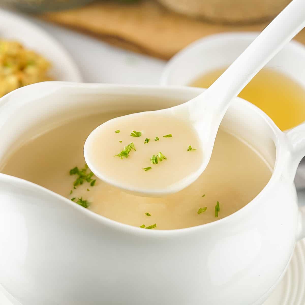 turkey gravy on a spoon with fresh parsley over a gravy boat