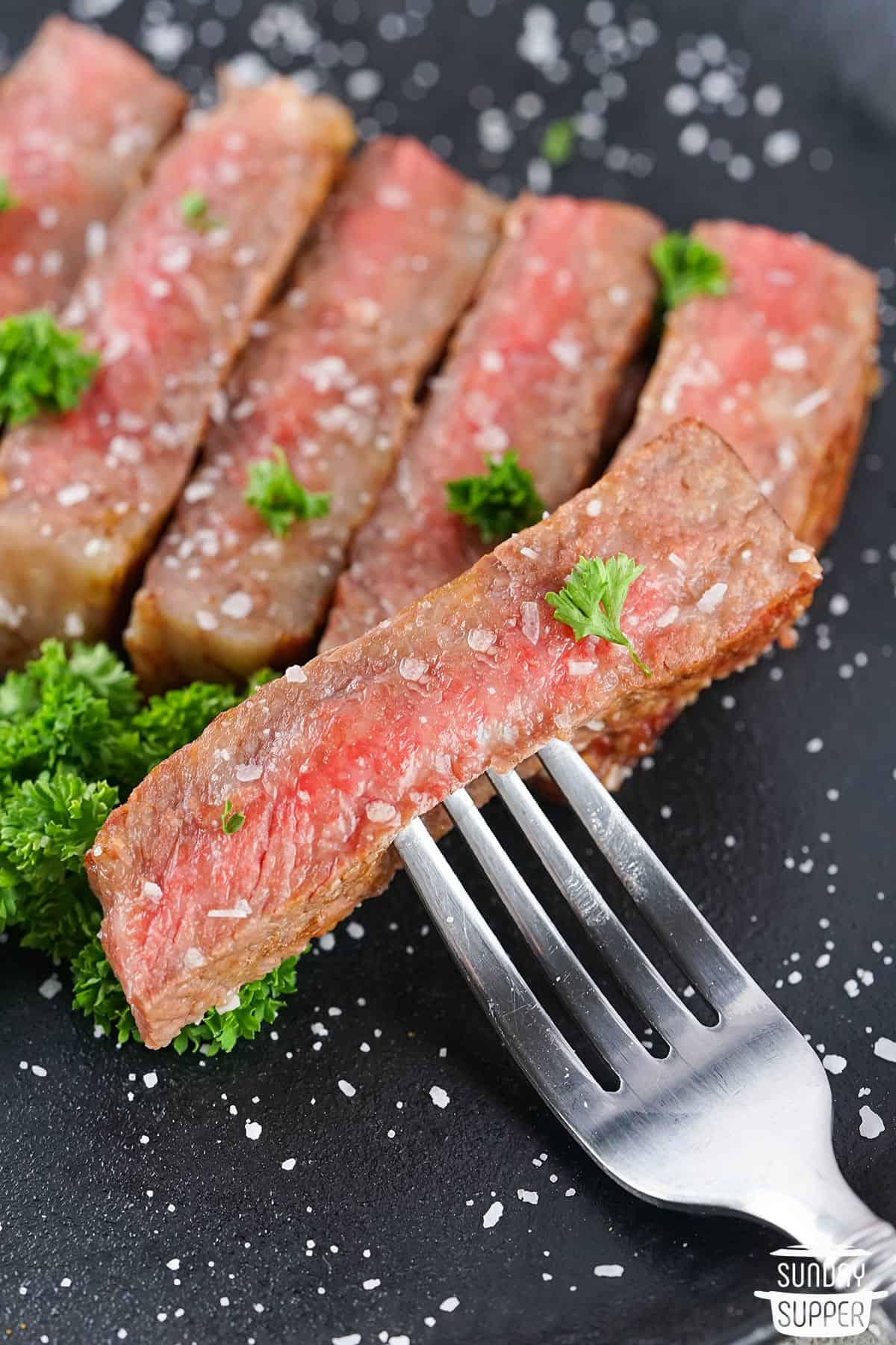 a fork holding up a slice of wagyu steak