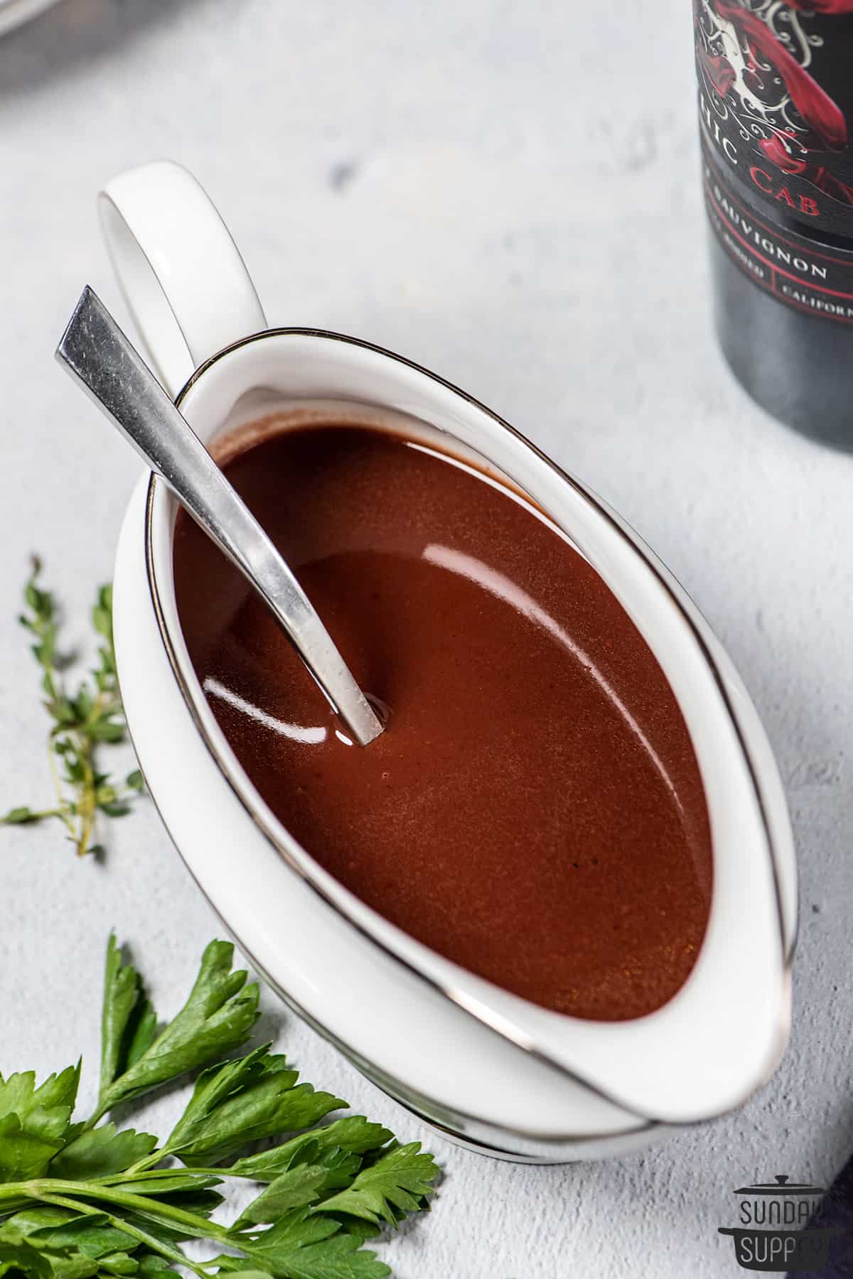 a gravy boat of espagnole sauce with a spoon