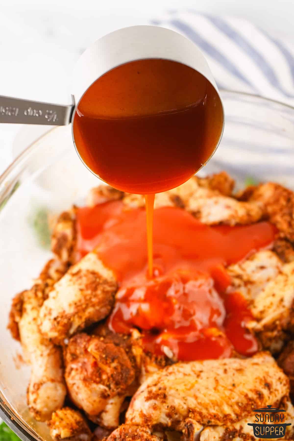 hot sauce being added to the seasoned chicken