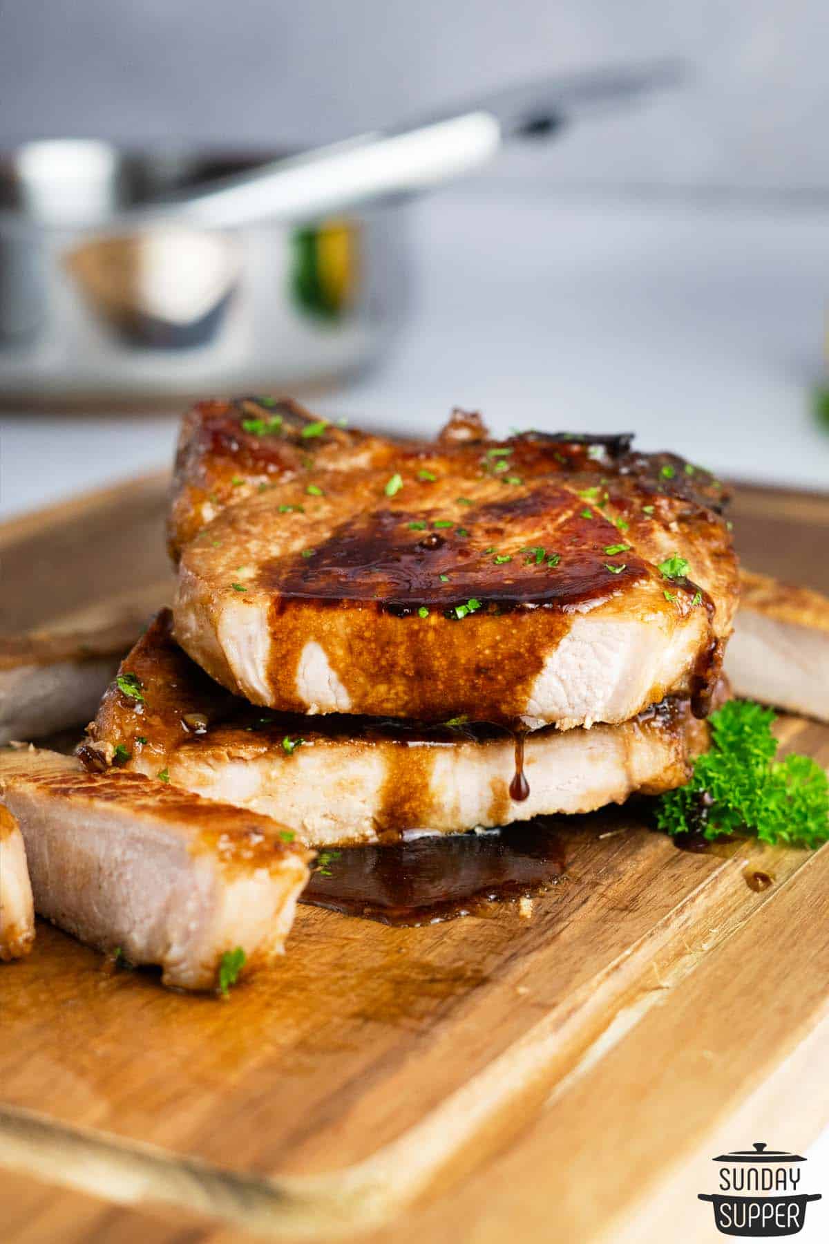 honey glazed pork chops on a cutting board, sliced and dripping with glaze