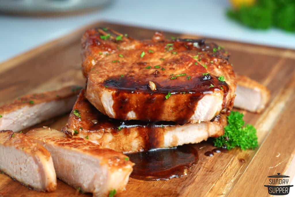 perfectly cooked honey glazed pork chops sliced on a cutting board with dripping glaze