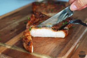 slicing pork chops thinly on a cutting board