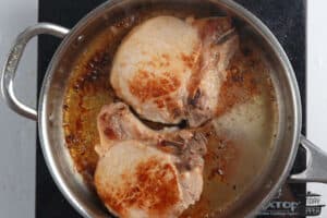pork chops browning in a skillet