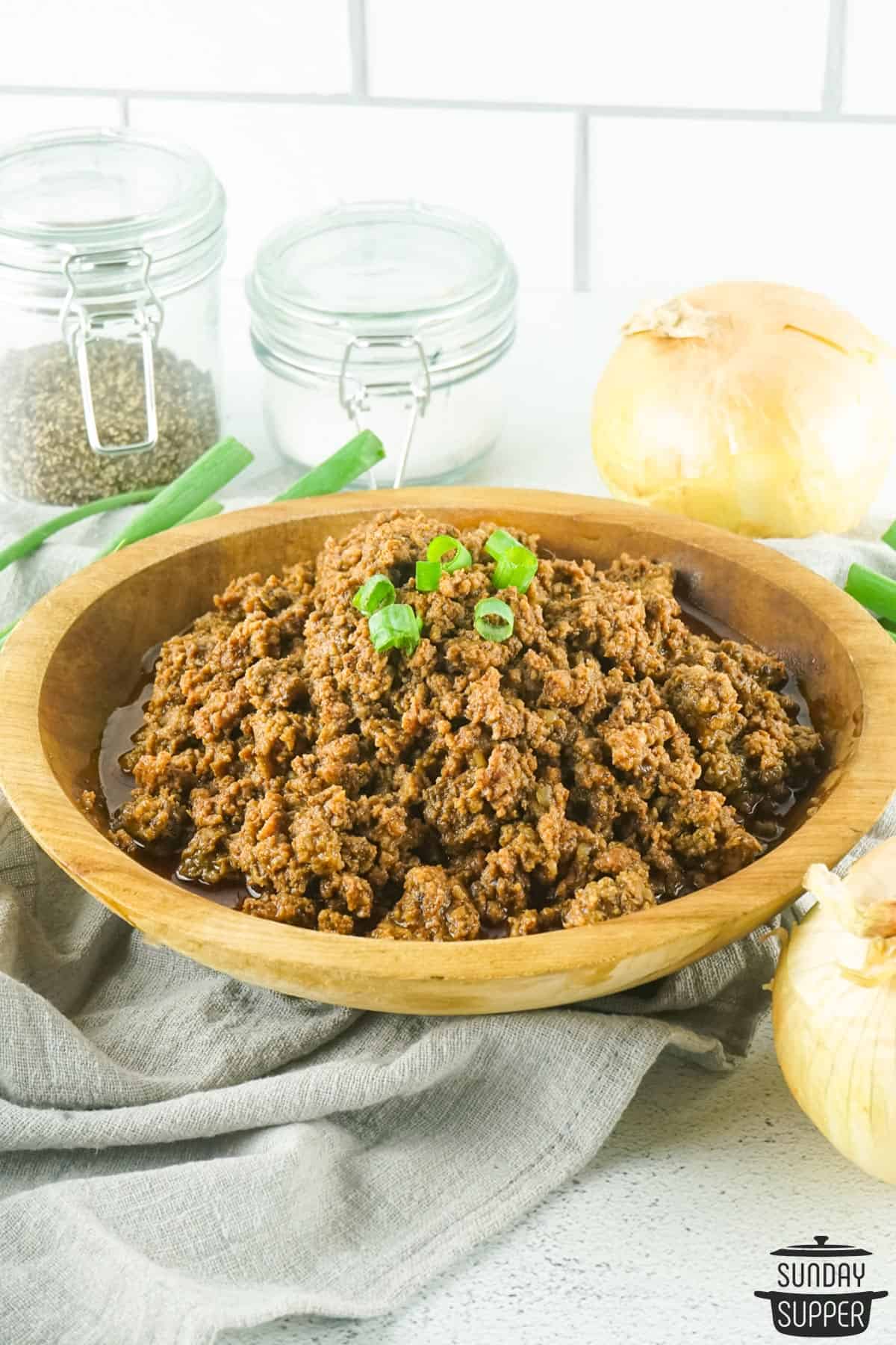 a bowl filled with taco meat on a counter with onions