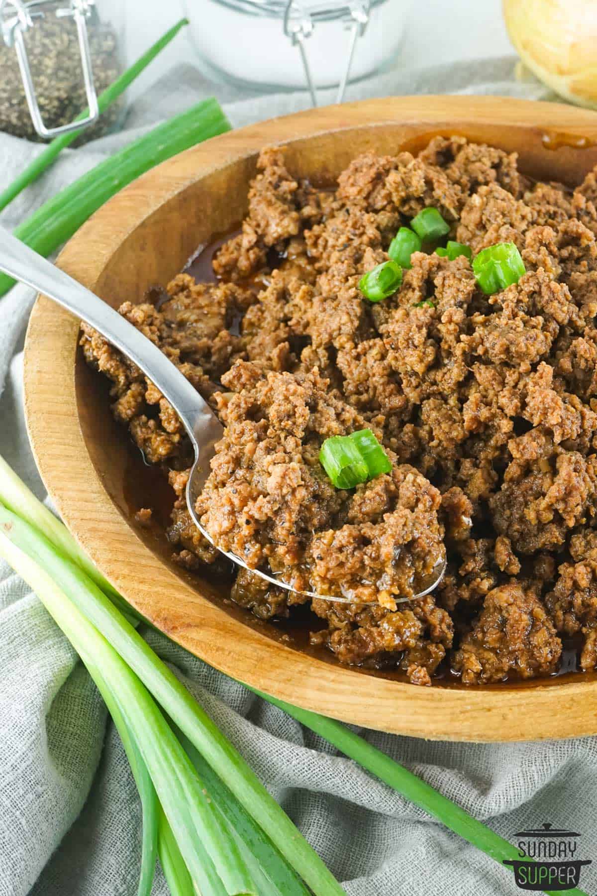 a spoon taking taco meat out of a bowl of taco meat