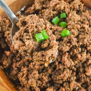 a spoon full of taco meat over a bowl