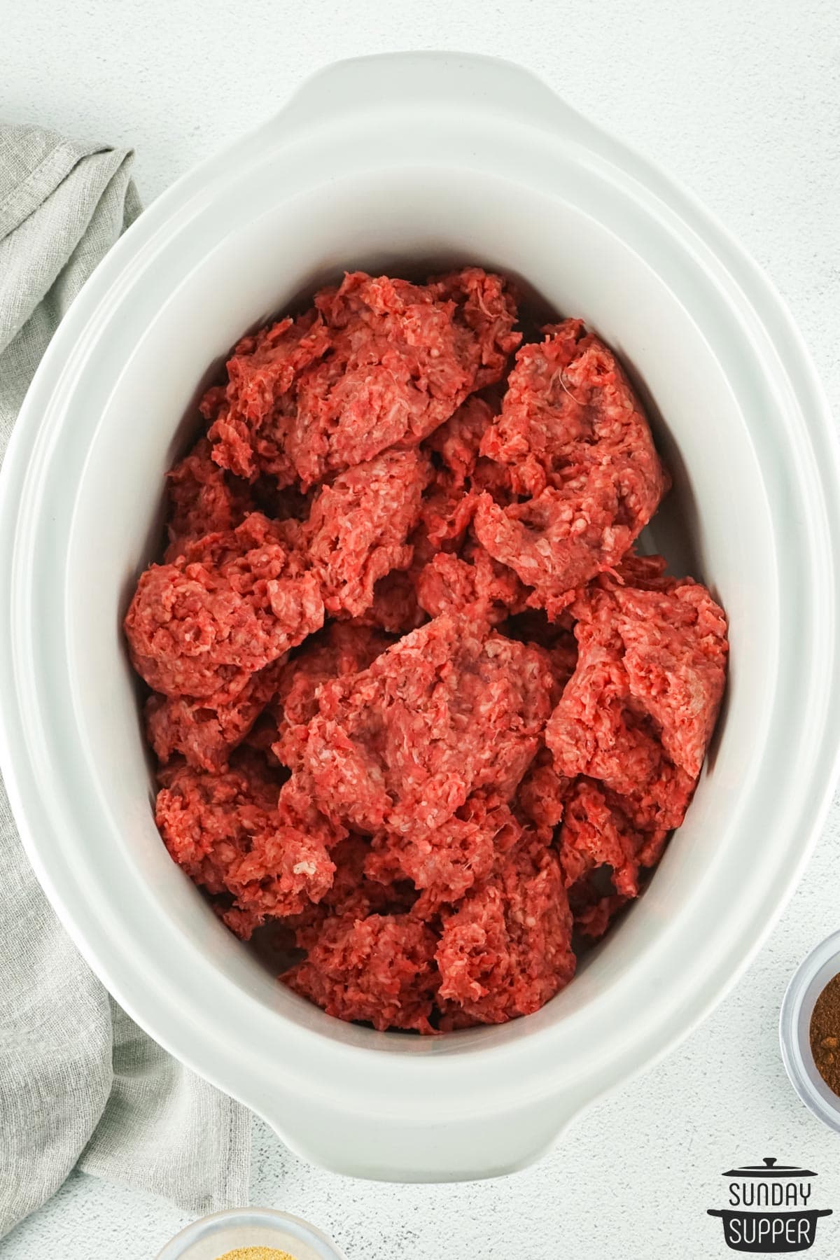 uncooked ground beef in a slow cooker pot